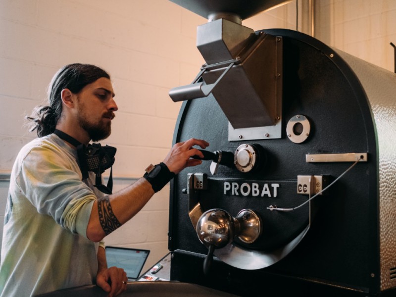 A man roasting coffee with a roasting machine.